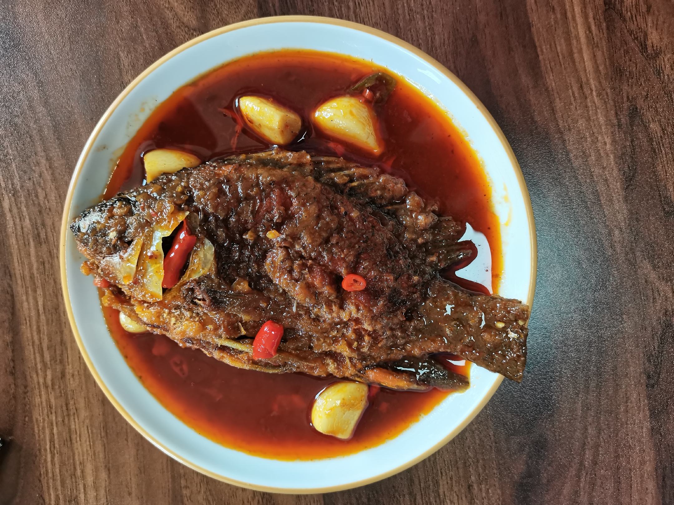 图中展示锅中正在炖煮的蒜苗烧鱼,汤汁浓郁,蒜苗与鱼肉交织 蒜苗烧鱼炖煮过程图