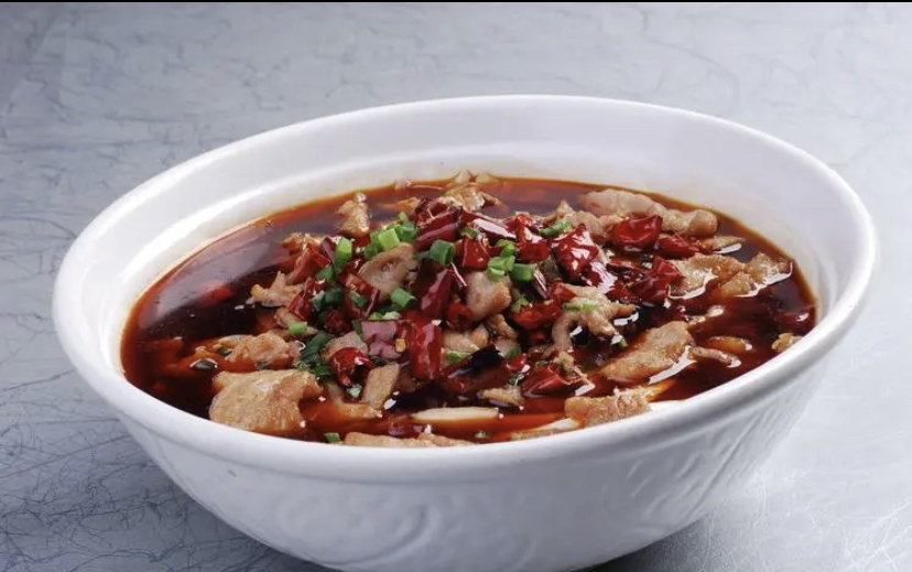 一盘红亮诱人的水煮牛肉,表面覆盖大量剪碎的干辣椒段,旁边配有小碟干小米辣碎末作为蘸料,体现干辣椒在中式热菜中的核心地位 干辣椒在菜肴中的应用实例