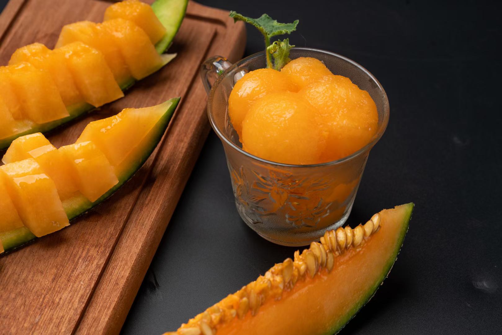 展示一杯新鲜制作的蜜瓜饮品,背景为夏日风格桌布,搭配切开的西州蜜瓜 蜜瓜饮品特写