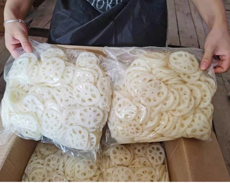 木质托盘上陈列多种绿莲藕衍生产品:透明袋装即食脆藕片、玻璃瓶装藕汁饮料、马口铁罐装藕粉、小包装冻干藕粒,背景为现代食品加工厂内景,体现产业化加工能力 绿莲藕深加工产品展示图