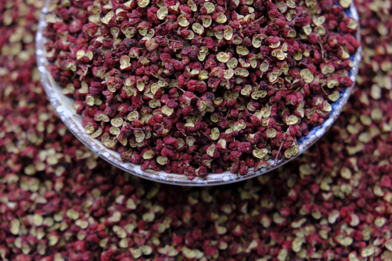 三类常见花椒并列展示:左为四川大红袍红花椒,中为青花椒(九叶青),右为干制藤椒,背景为木质托盘,突出颜色与形态差异 不同类型花椒对比图