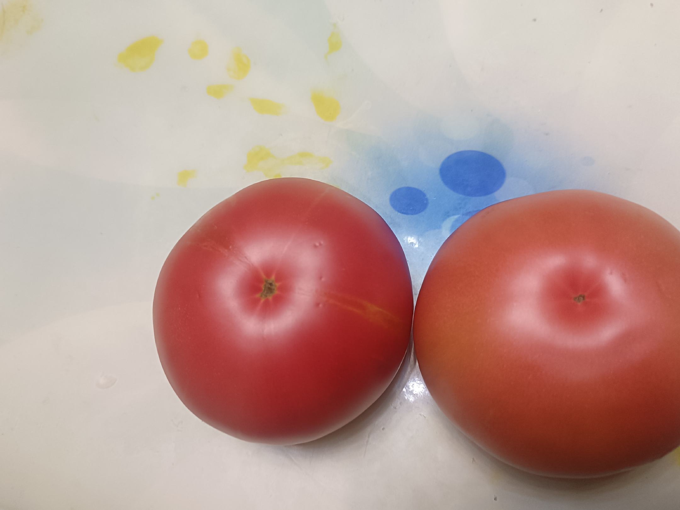 一位厨师正在操作台上对两个红色硬粉西红柿进行处理:先在顶部划十字刀口,接着将其放入冒着热气的锅中焯水,随后捞出放在砧板上用手剥皮,最后用刀切成大小均匀的滚刀块,旁边配有去皮后的完整果肉特写 西红柿去皮与切块过程