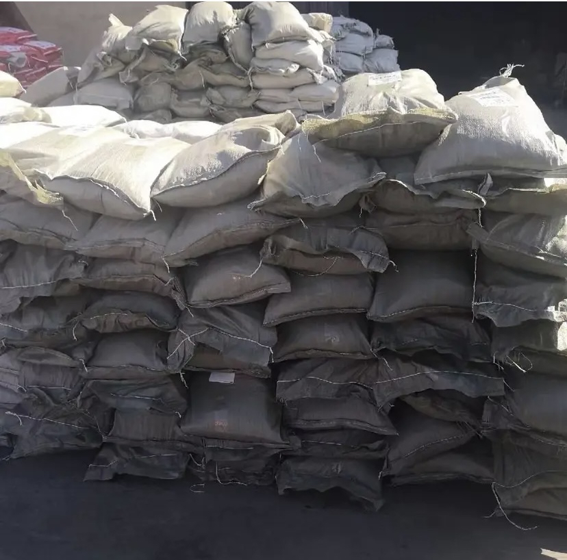 平菇基地菌渣资源化处理车间：传送带输送深褐色干燥菌渣进入双轴搅拌机，右侧工人正将活体赤子爱胜蚓均匀撒入发酵槽，槽内可见蚯蚓活动痕迹及初步形成的团粒状蚯蚓粪