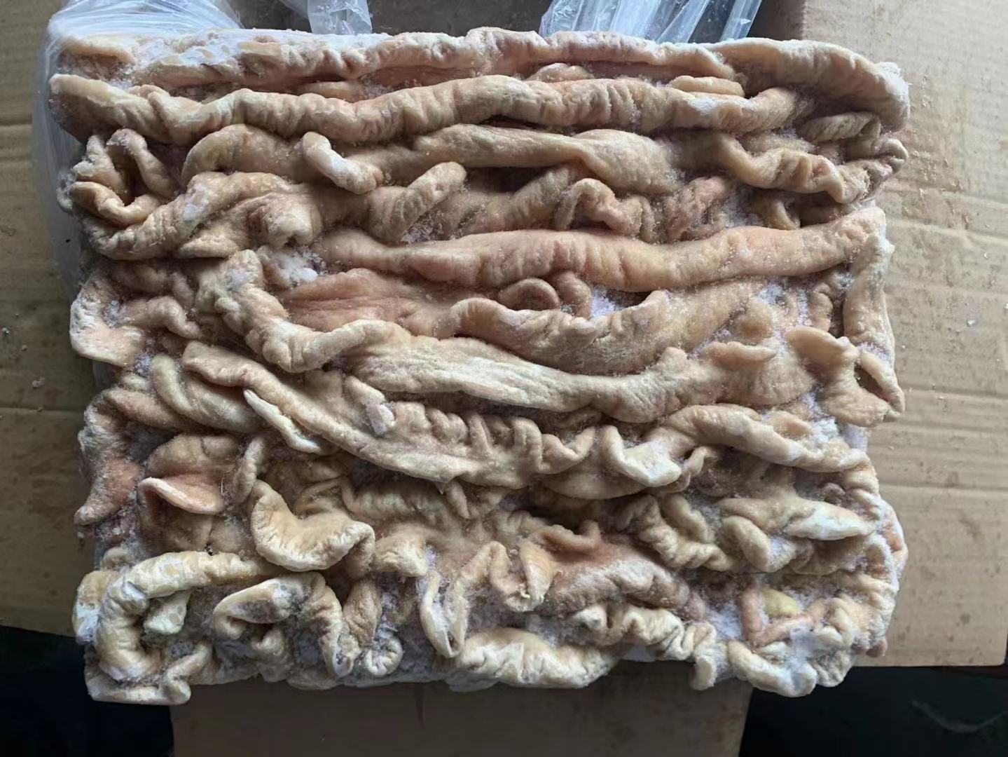 展示新鲜猪大肠在清水盆中被手工清洗的过程,旁边摆放着盐、面粉等清洁材料 猪大肠清洗过程