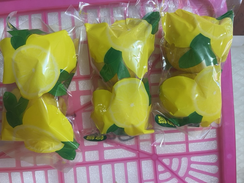 一位女性消费者在农贸市场摊位前用手轻轻按压安岳柠檬,对比不同果实的颜色与形状,摊位招牌标注‘正宗四川安岳柠檬’,周围摆放整齐的黄色柠檬筐,背景可见其他顾客驻足选购 消费者在市场挑选安岳柠檬特写