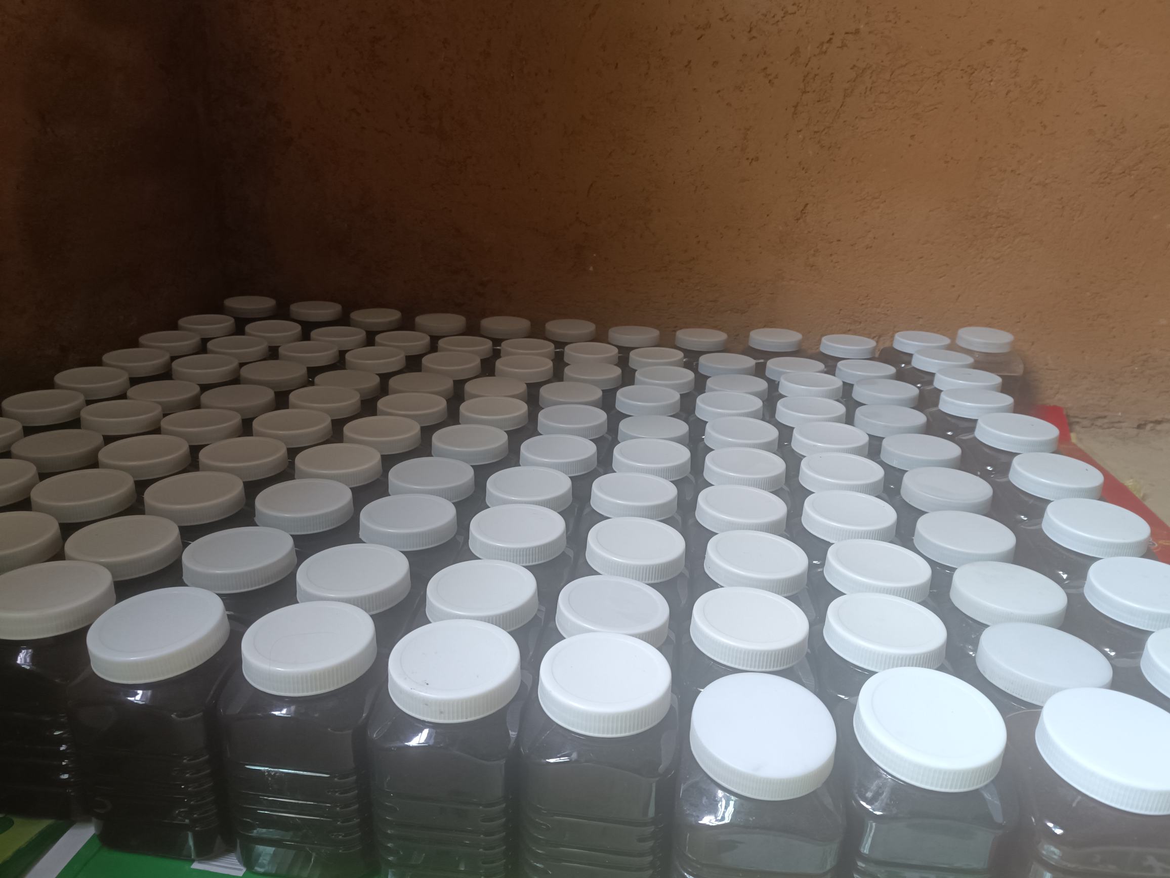 木桌上摆放两组天然食材:左侧为透明密封罐装的干制野菊花,花朵清晰可见;右侧为玻璃瓶装结晶态土蜂蜜,旁边放有一把木勺与新鲜柠檬片,整体风格质朴自然,突出农产品原生态品质 野菊花与蜂蜜组合摆拍