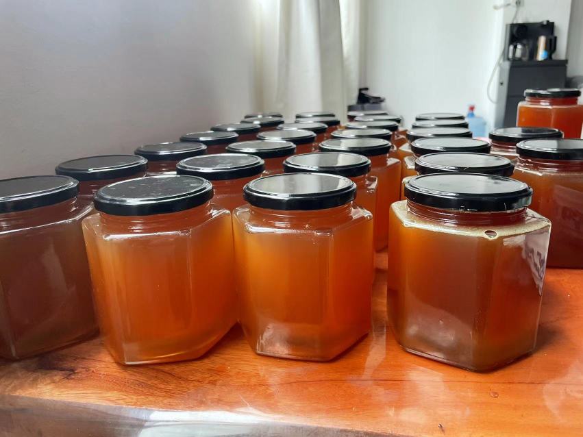 玻璃瓶中的结晶蜂蜜,表面呈现颗粒状结构,背景为木质桌面,展示蜂蜜自然结晶状态 蜂蜜结晶现象