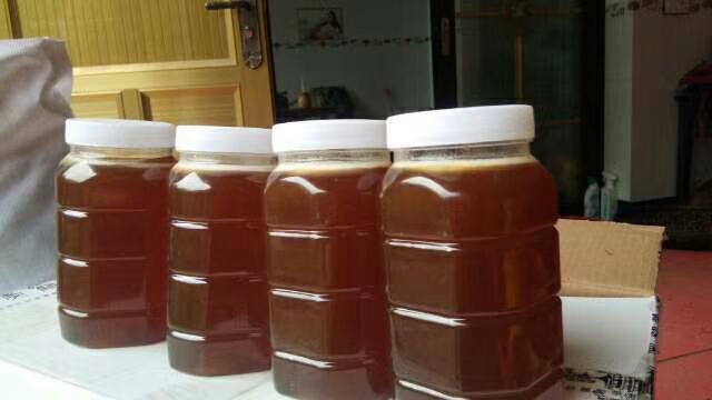 玻璃罐中糖醋蒜呈现琥珀色,液体清澈透亮,摆放于木质餐桌上的特写照片 糖醋蒜成品展示图