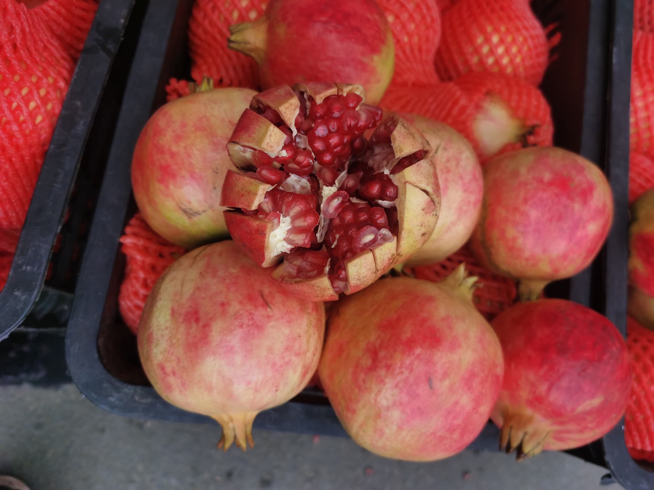 新鲜石榴与切开后的果肉特写图