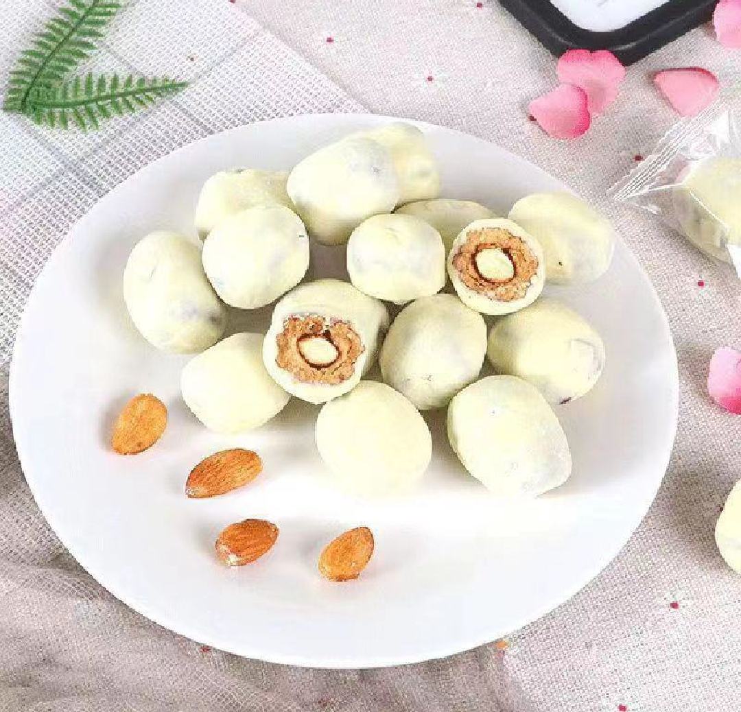 一名穿着食品级工作服的手工制作者正在操作台前拉伸奶枣混合物,手中拉出白色丝状质地,案板上有去核长枣、奶粉堆、融化的黄油碗,背景虚化显示整齐排列的成品奶枣 奶枣制作过程特写