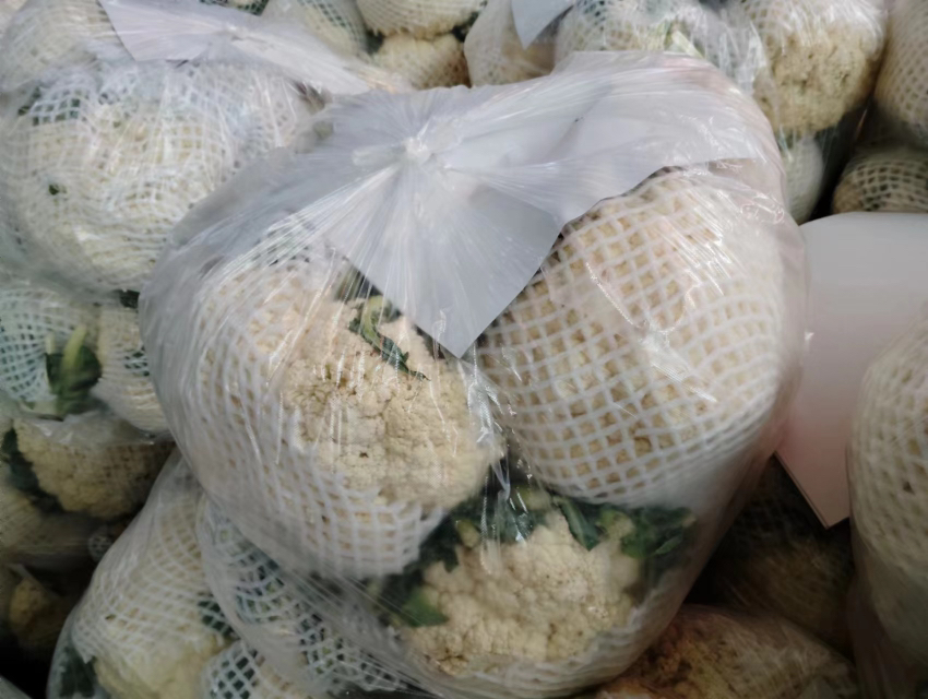 图中展示两款分别标注“湖南野菊花”与“东北蒲公英”的农产品包装袋,背景为木质桌面,体现自然健康理念 野菊花蒲公英包装展示图