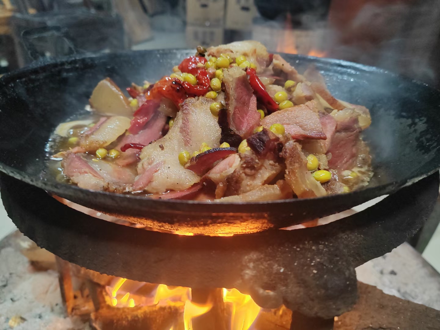 一位农家妇女站在传统土灶前,手持锅铲正在铁锅中翻炒切好的雷竹笋,锅中热气腾腾,旁边摆放着葱姜蒜和酱油调料,背景是木质橱柜和悬挂的腊肉,展现出浓郁的乡土生活气息 农家厨房中正在翻炒雷竹笋的场景