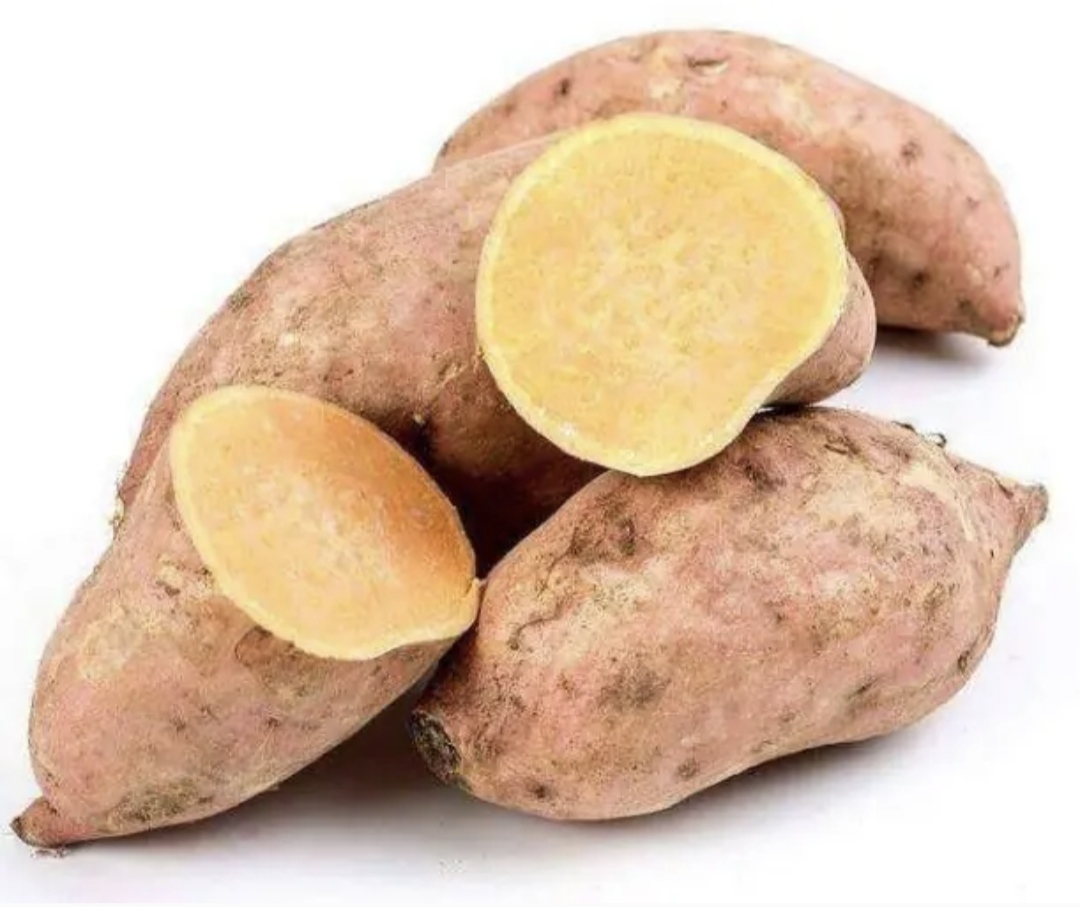 一根新鲜采摘的龙薯,表皮土黄色略带红晕,表面干净无破损,切开后露出鲜艳的橙黄色肉质,质地细腻无纤维感,背景为木质砧板和厨房刀具 新鲜龙薯特写