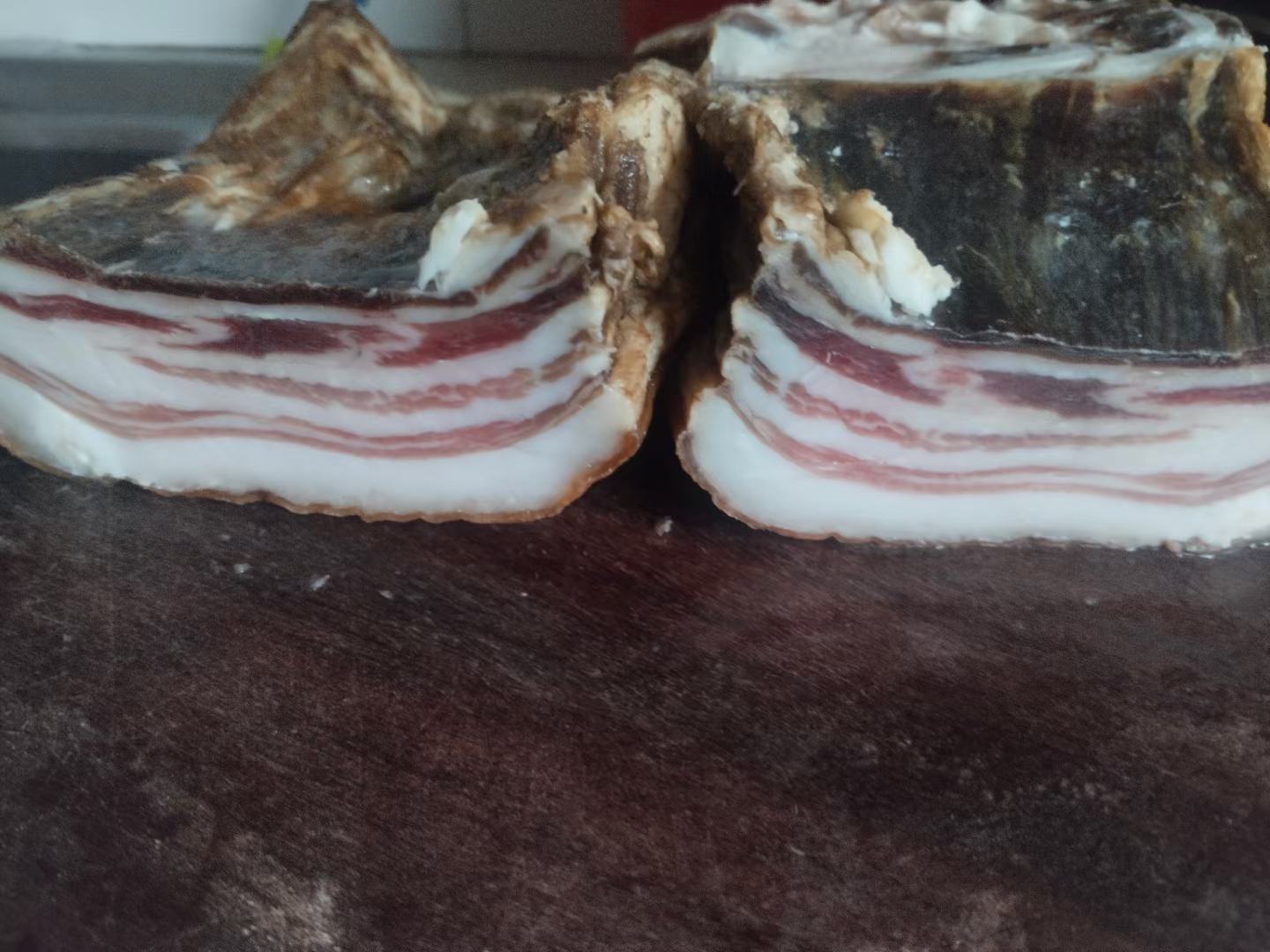 展示新鲜红菜薹与腊肉的原始食材,摆放在木质案板上 红菜薹和腊肉的特写图