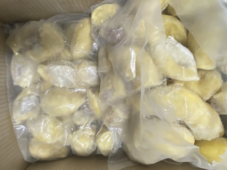 透明真空包装盒内装有两瓣完整的金黄色金枕头榴莲果肉,置于白色泡沫托盘上,陈列于超市冷藏柜中,背景可见其他冷冻水果标签,温度显示为-18℃ 超市冷柜中陈列的真空包装金枕头榴莲果肉