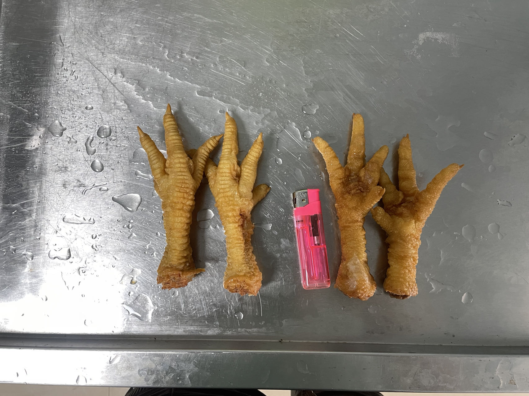 展示泡椒凤爪在锅中加热的画面,锅边有泡椒、姜片等配料,背景为厨房环境 泡椒凤爪加热处理场景图