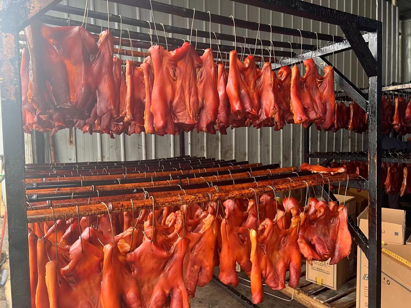 几只腊鸡腿悬挂在阳台木架上，背景为清晨微光，空气清新，鸡腿表面已形成轻微油亮层