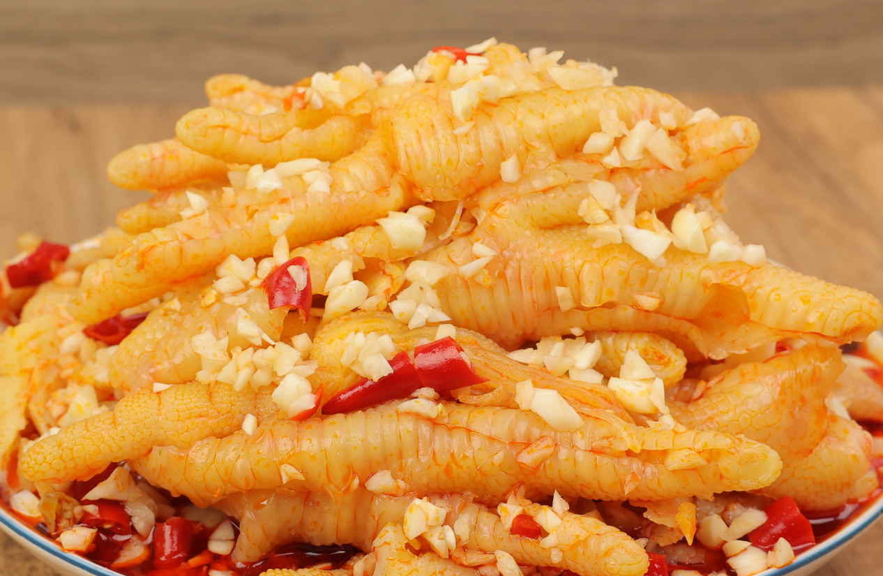 盘中盛放着色泽诱人的蒜香鸡爪,表面覆盖一层蒜末和辣椒碎,香气四溢 蒜香鸡爪成品图