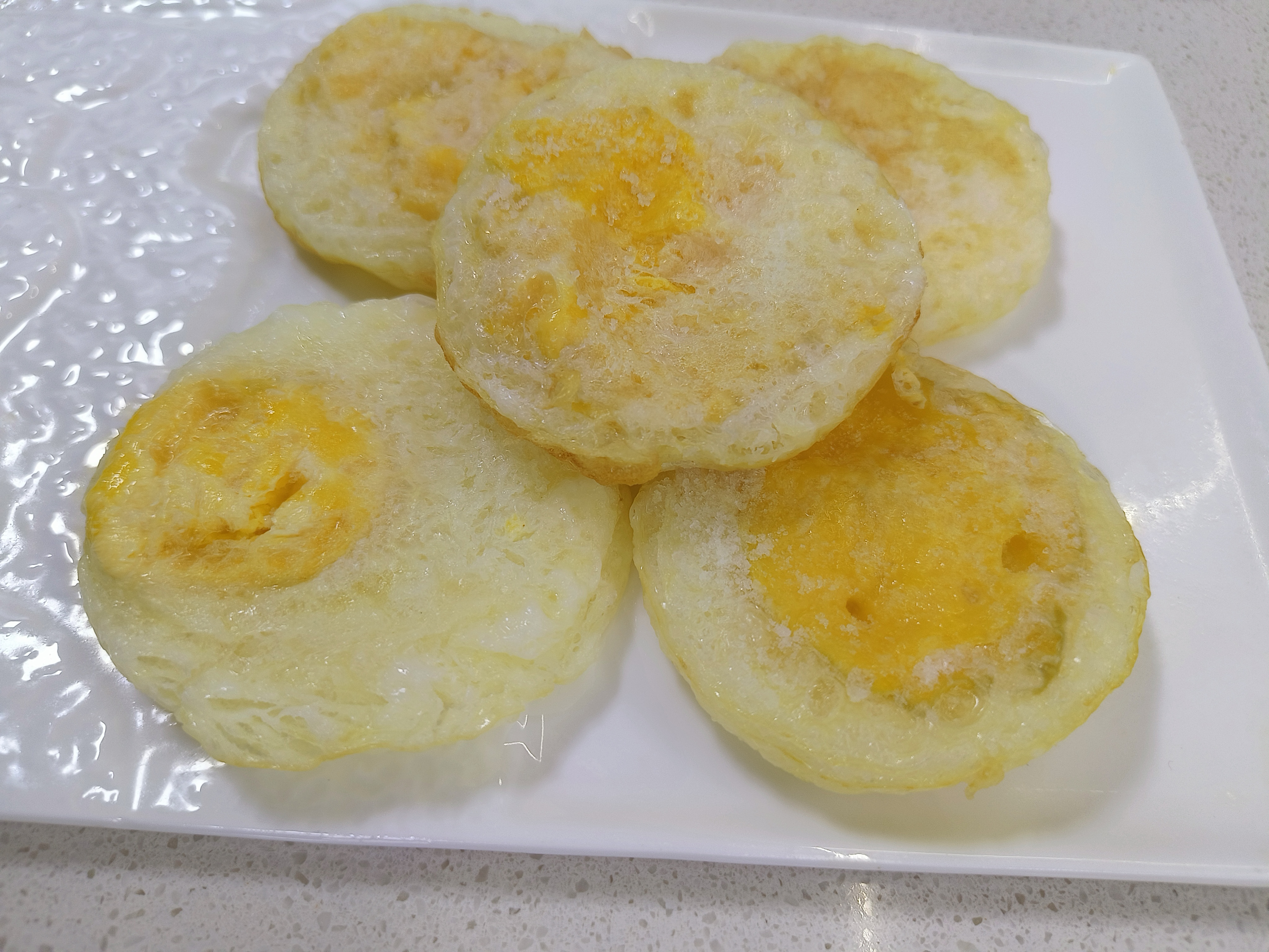 色泽金黄的蛇皮炒鸡蛋盛放在白色瓷盘中,旁边点缀葱花 蛇皮炒鸡蛋成品图