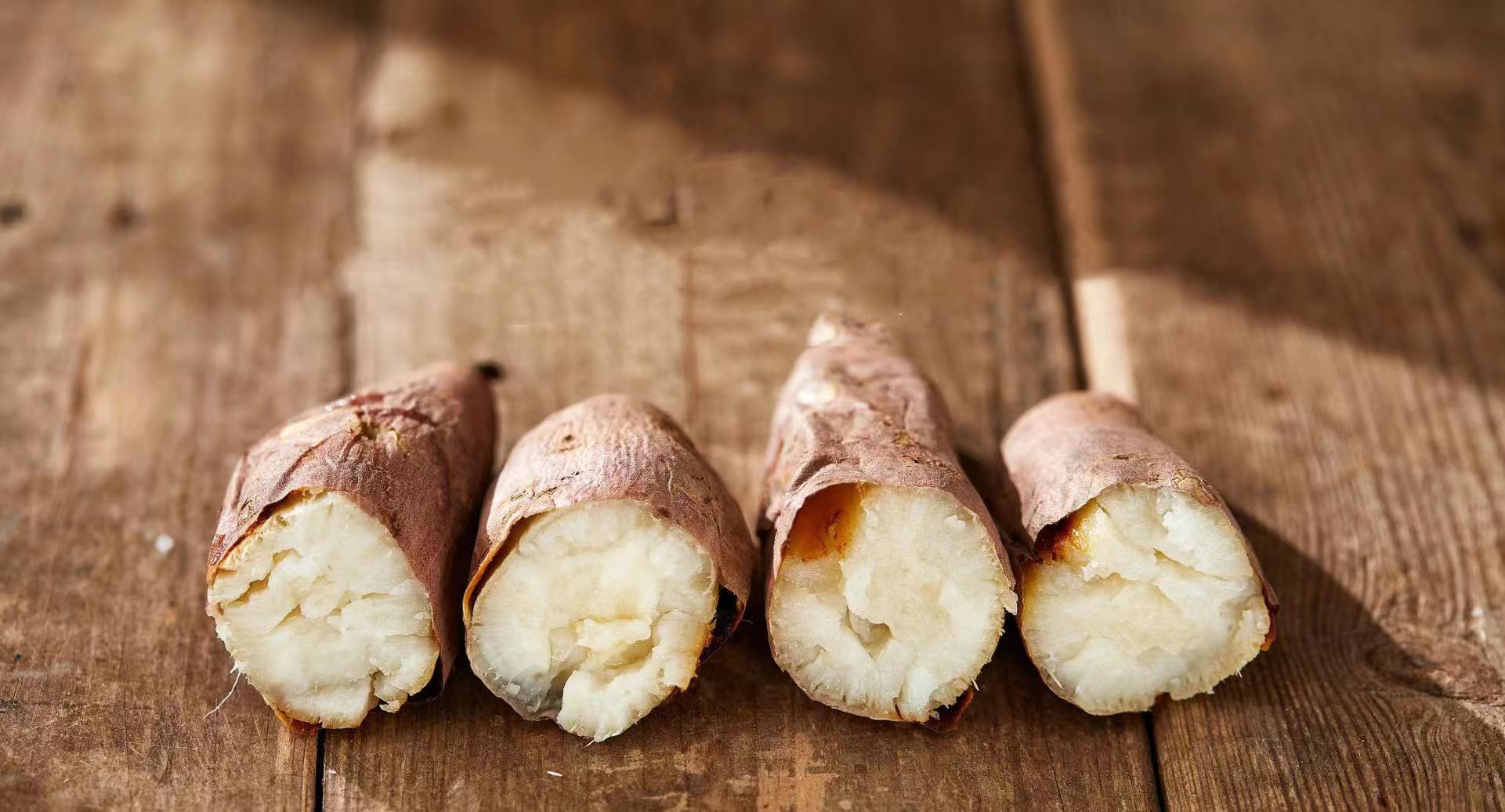 新鲜的红薯整齐摆放在厨房台面上,背景为木质桌面,光线柔和 红薯展示图