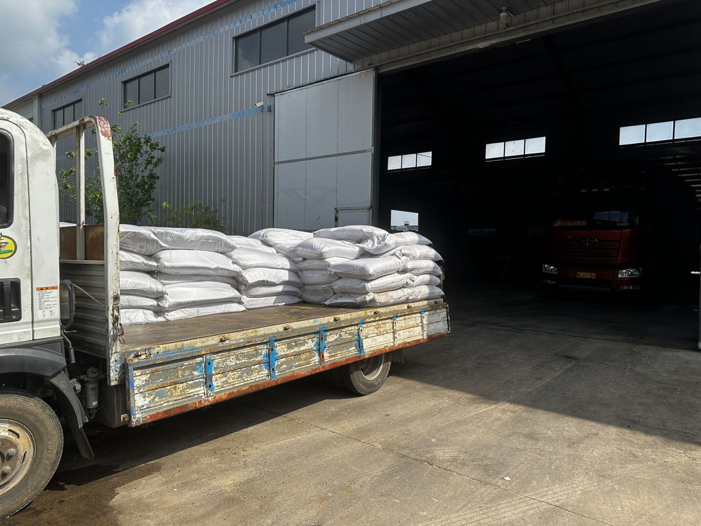 一辆卡车正在卸载大豆,背景为大型粮仓,突出物流与仓储主题 大豆装卸运输场景