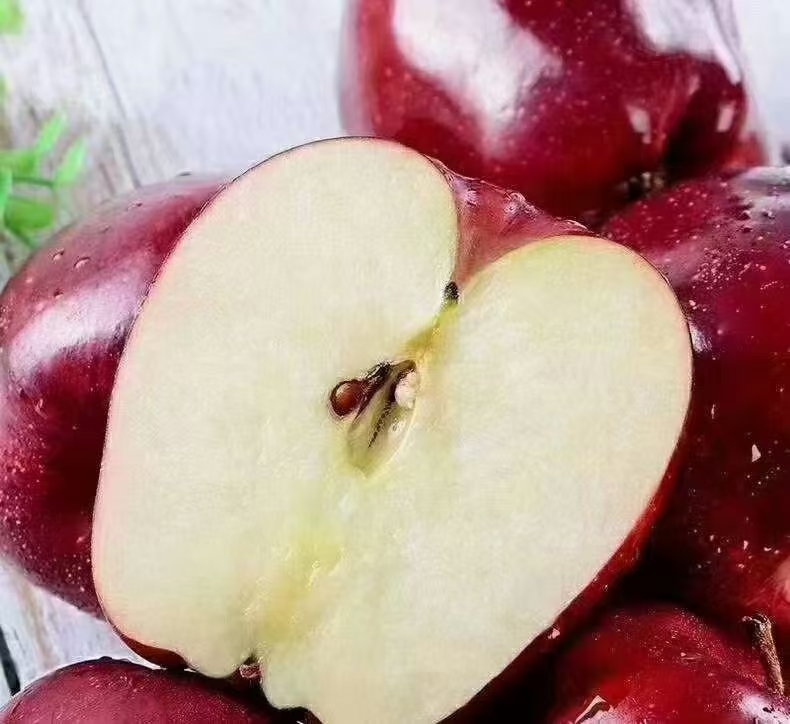 一个刚切开的花牛苹果,露出洁白细腻的果肉和清晰的籽室结构,汁水饱满,背景虚化显示厨房台面,强调食材新鲜与即时享用的重要性 新鲜切开的花牛苹果横截面特写