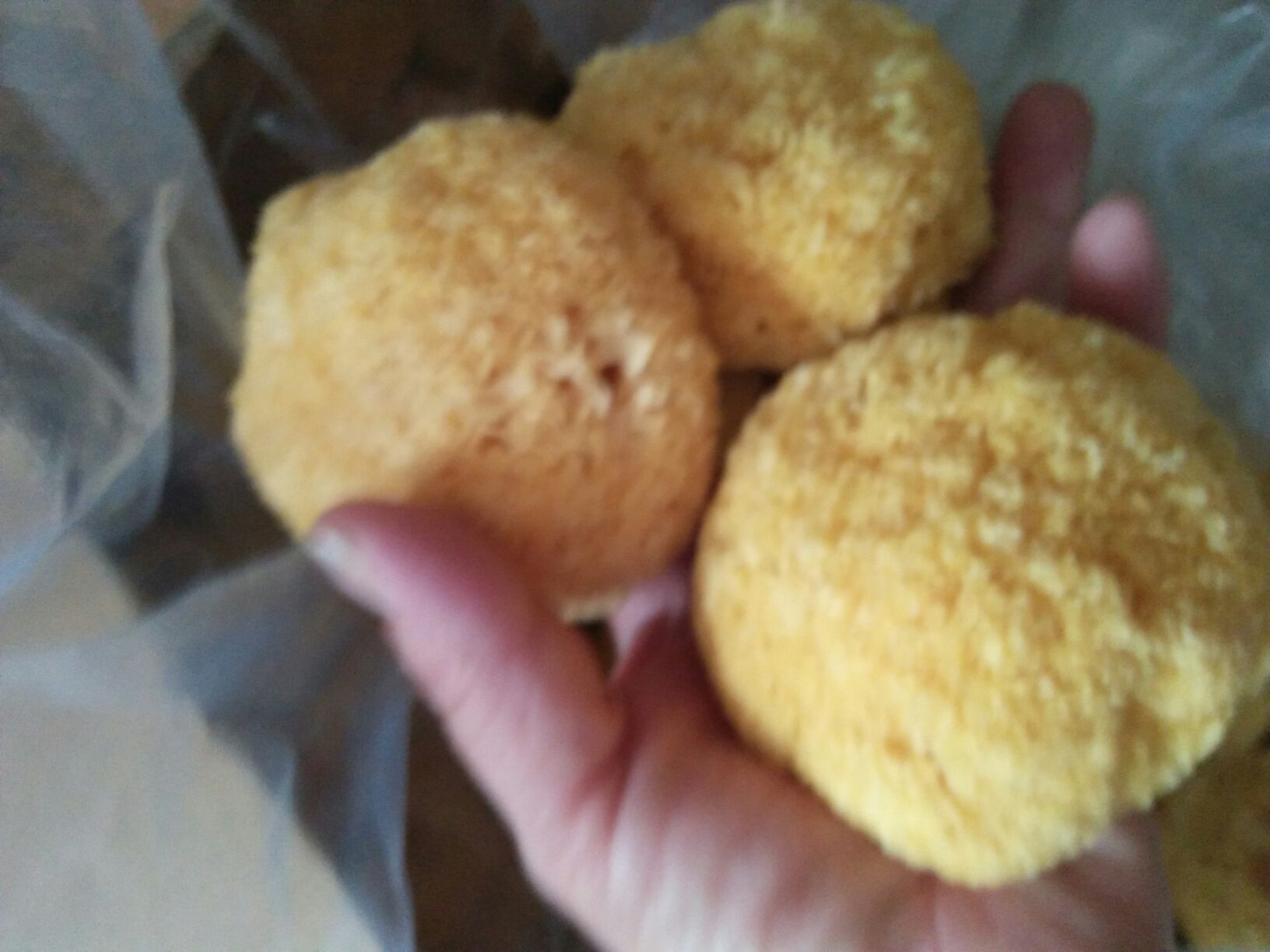 一只手正在用清水冲洗一碗干的小朵银耳,银耳呈米黄色,水中漂浮少量木屑,背景为白色陶瓷碗和竹制厨房台面 清洗干银耳