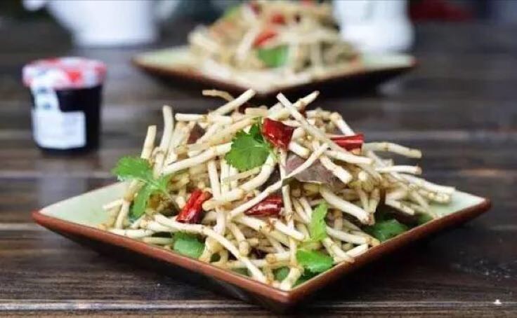 专业美食摄影:呈现符合食品安全规范的凉拌鱼腥草根标准出品——食材新鲜度可视(根段挺括无萎蔫)、调味简约(无过量油脂与人工色素)、器皿洁净(青瓷盘凸显食材本色),体现‘药食同源’的视觉信任感 凉拌鱼腥草根成品:青白相间根段整齐铺于青瓷盘,淋琥珀色米醋汁,点缀嫩姜丝、蒜末与金黄芝麻,背景虚化呈现竹制凉菜架与玻璃调料瓶