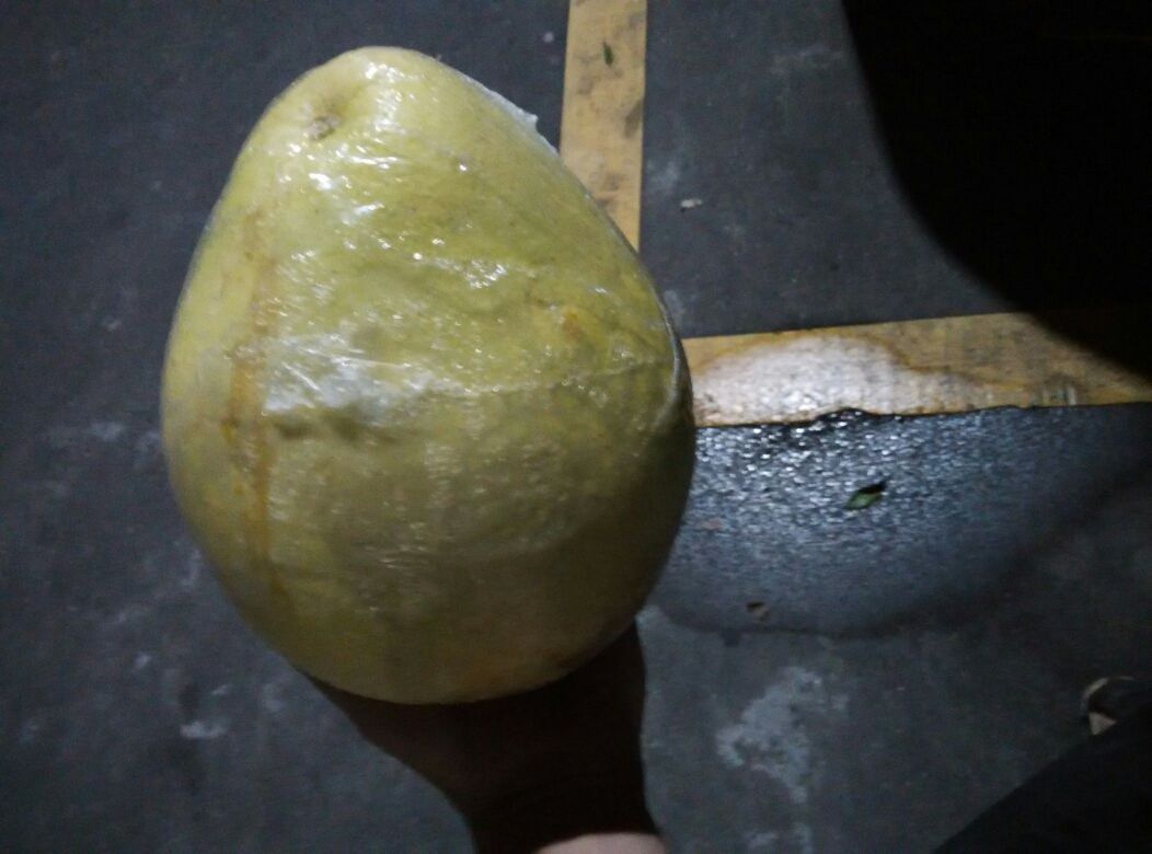 一张白色桌面上展示一个正在被保鲜膜包裹的柚子,镜头聚焦于手部操作细节,保鲜膜紧密贴合柚子表面,尤其覆盖果蒂部位,形成完整密封层 单个柚子用保鲜膜包裹局部特写