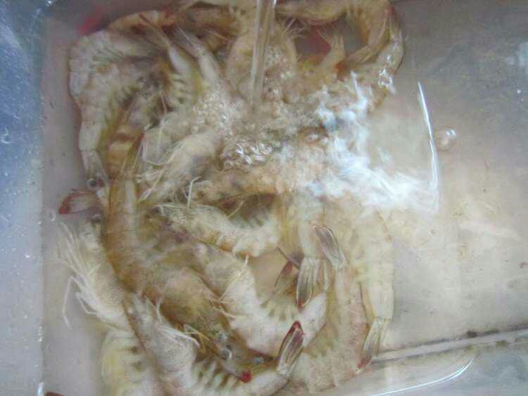 对虾在透明容器中整齐摆放，色泽鲜亮，背景为海鲜市场环境