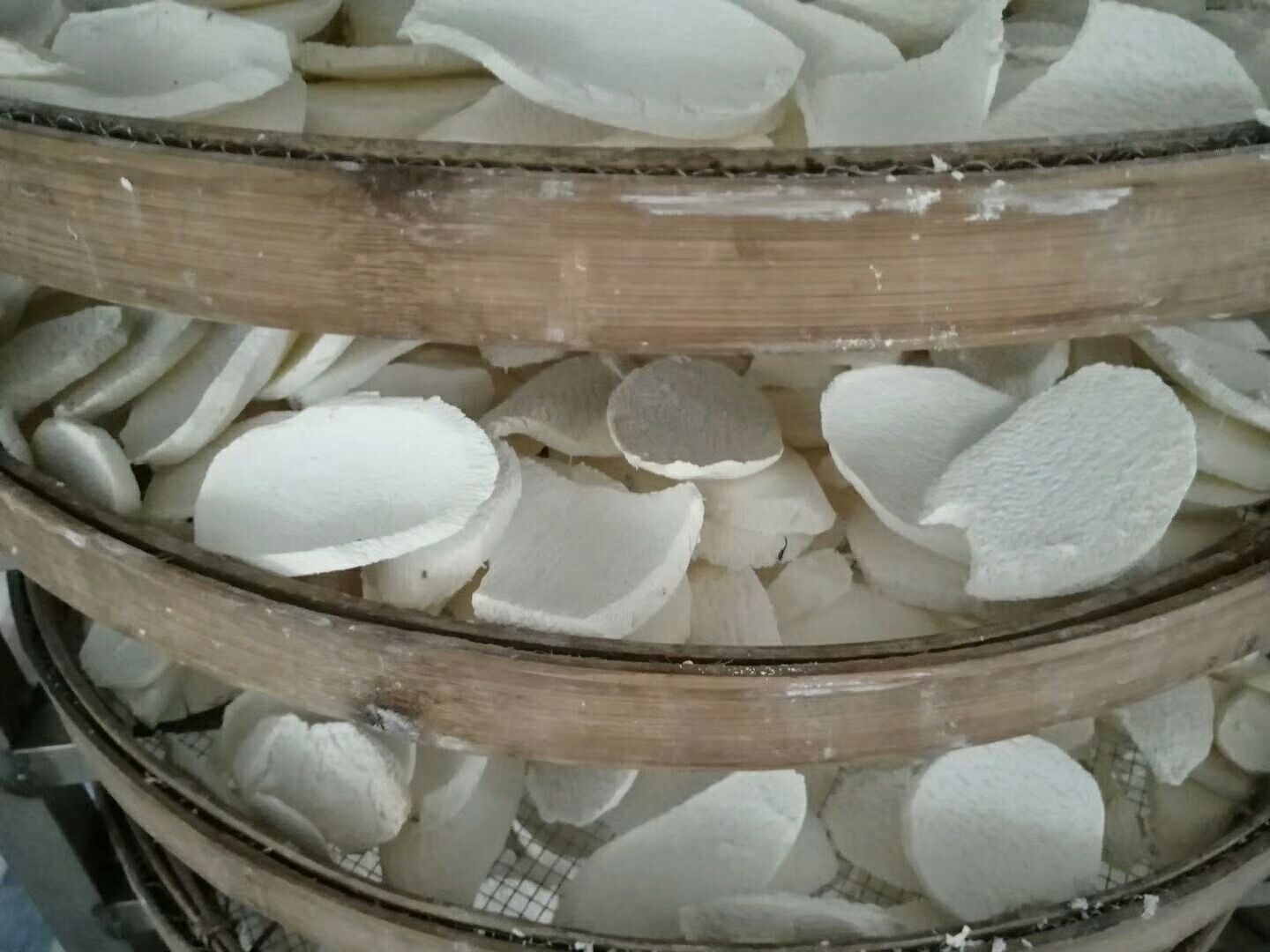 一张展示药用山药传统炮制工艺的图片,包括清洗、去皮、切片、晾晒四个步骤:左侧为农民在水边清洗带泥的山药,中间为手工切片,右侧为竹席上铺满山药片正在进行日光晾晒,背景为秋季晴朗天空,体现传统加工流程的真实场景 药用山药炮制过程示意图