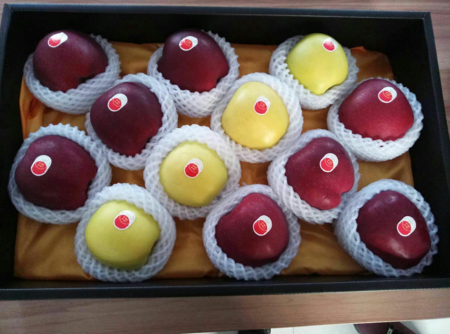 淳化县苹果产业园区内的现代化包装车间,工人正在对黄元帅苹果进行礼盒封装,背景展示‘淳化苹果’地理标志商标和二维码溯源系统,体现品牌化与数字化管理 淳化县苹果品牌展示与包装车间