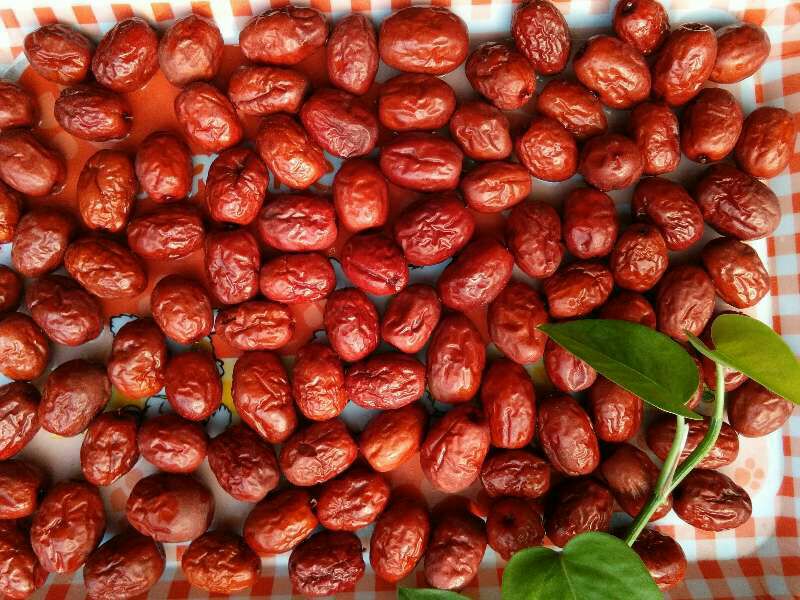 一组精美包装的金丝小枣夹心枣礼盒陈列在木质桌面上,包装设计融合中国风元素,如祥云纹、书法字体,盒内分格摆放不同口味夹心枣,旁边配有中式茶具,营造出高端礼品氛围 金丝小枣夹心枣礼盒展示