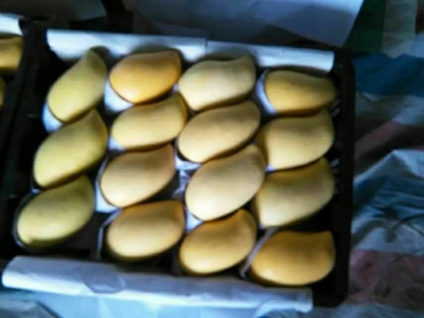 透明包装袋中装有数片金黄色的鹰嘴芒果干,果片完整、色泽均匀、表面无结晶,旁边摆放新鲜鹰嘴芒果作为对比,背景为现代化食品加工厂内景 鹰嘴芒果干产品展示