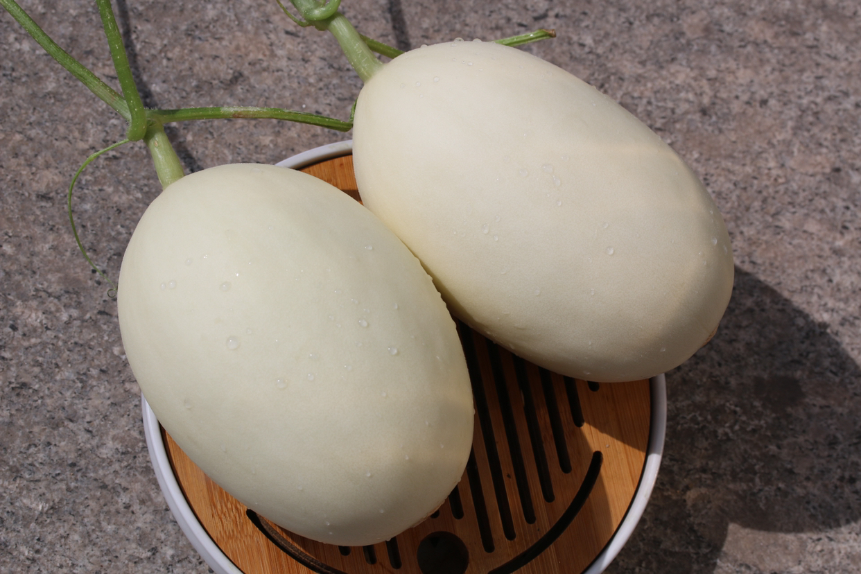 翠梨甜瓜与其他夏季水果摆放在木质托盘上，背景为阳光洒落的厨房台面，营造出温馨的居家氛围