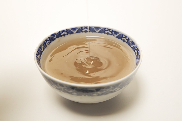 高清实拍:浅青釉瓷碗盛装淡琥珀色粉葛水,液体澄澈微稠,表面泛柔和淀粉光泽;碗沿斜置一小撮金黄色陈皮丝;右侧放置医用电子温度计,屏幕清晰显示42.0℃,体现适宜温服温度 粉葛水成品盛于青瓷碗中,表面浮有细微淀粉光泽,碗旁配新鲜陈皮丝和温度计显示42℃