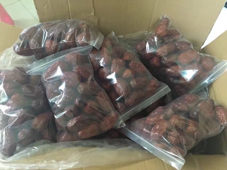 一个透明玻璃密封罐内装满深红色的和田大枣,放置在厨房干燥柜中,旁边配有标签纸注明购买日期和保质期,环境整洁避光 家庭厨房中储存和田大枣的正确方式