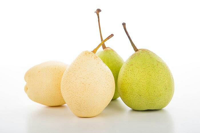 新鲜鸭梨特写 新鲜翠绿多汁的成熟鸭梨整齐摆放在木质砧板上,背景有淡淡的厨房光线,突出水果的新鲜质感