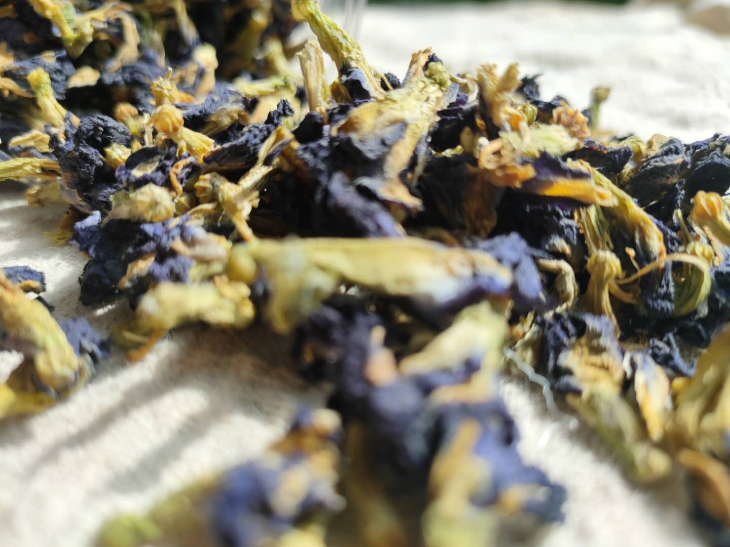 高分辨率产品图:透明玻璃杯盛装200mL蝶豆花柠檬饮,呈现清澈钴蓝色液体,杯壁附着细微气泡;杯旁放置食品级标签卡,标注:每份含花青素18.6mg、维生素C22.5mg、有机酸总量1.8g;背景为有机农场蝶豆花种植基地航拍图 蝶豆花柠檬饮成品与营养标签