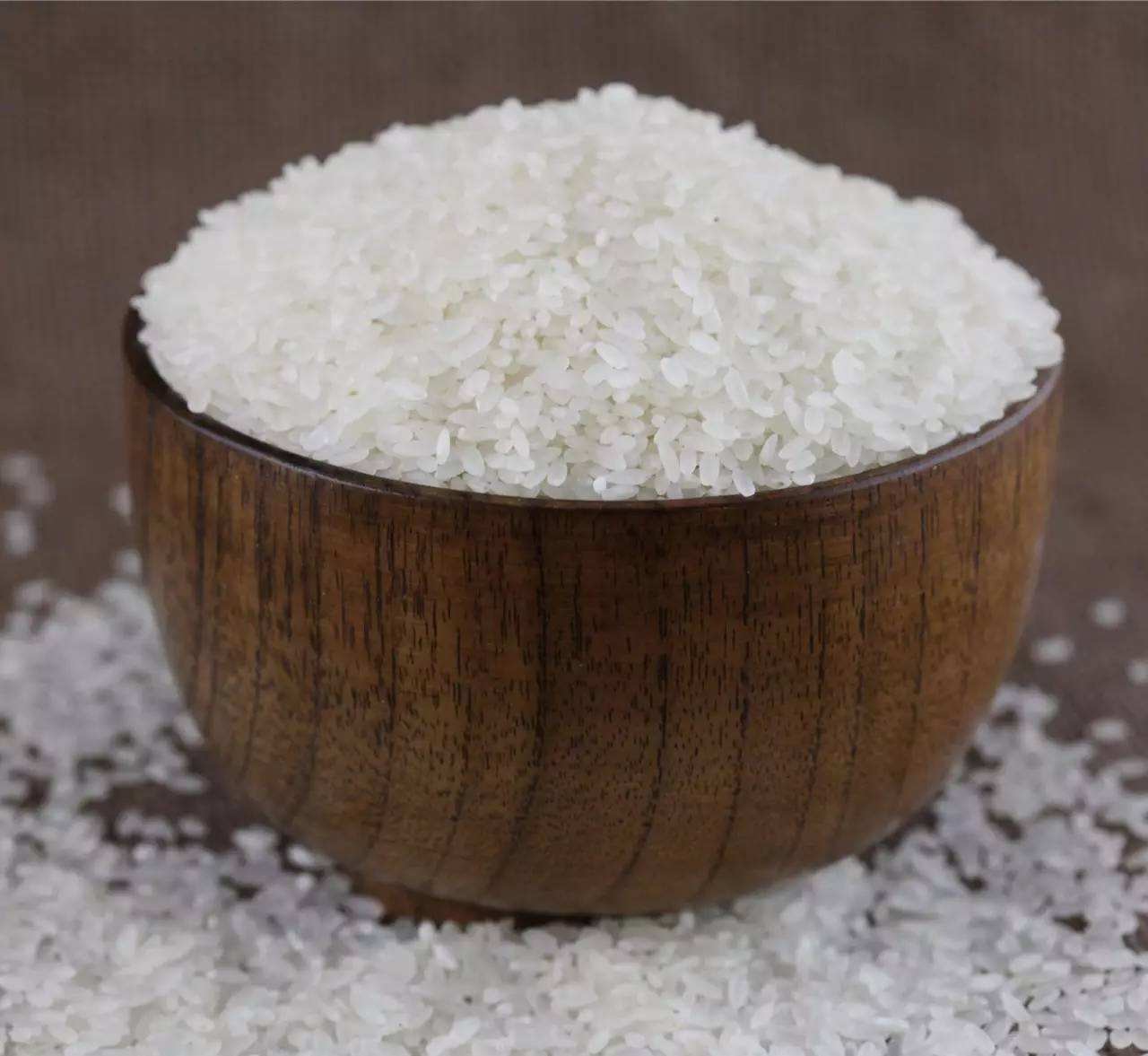 现代厨房环境中,一位家庭主妇打开电饭煲盖子,白色蒸汽升腾,锅内米饭晶莹剔透、颗粒分明,表面泛着自然油光,旁边配有木制饭勺和青花瓷碗,桌面上放置一袋印有‘五常大米长粒香’字样的透明真空包装米,展现高品质大米的日常食用场景 五常大米家庭烹饪实景图