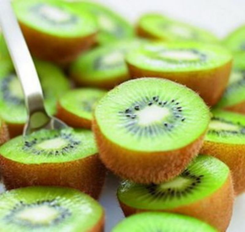 绿心猕猴桃切开特写，果肉呈翠绿色，黑色种子均匀分布，汁液饱满