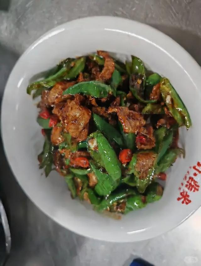 一盘以青小米椒为主料制作的湘菜小炒肉，青红小米椒切圈与瘦肉片同炒，色泽鲜艳，油光发亮