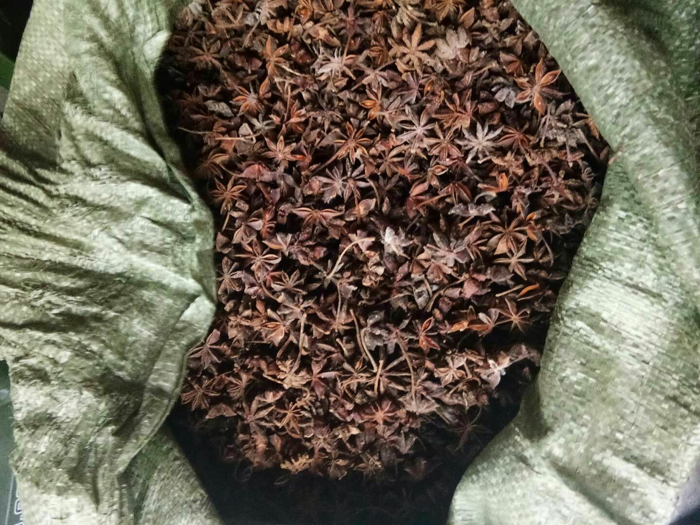 传统五香粉制作场景：青石臼中盛放八角、桂皮段、小茴香籽、花椒粒与丁香，一位老师傅手持木杵正在研磨，木屑与香料碎末微微扬起，暖光映照下散发温润光泽