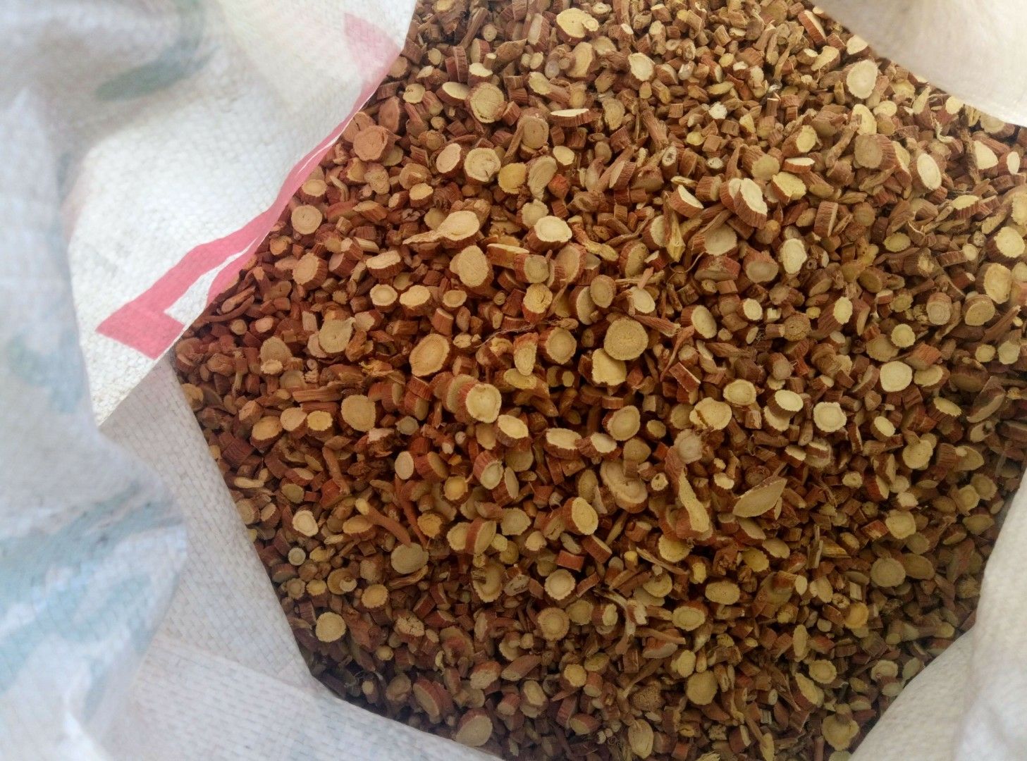 新鲜金桔与干燥甘草片并列摆放,背景为传统中药铺木质柜台,左侧为绿色带柄的完整金桔果实,右侧为棕褐色切片状甘草,两者之间有少量研磨成粉的甘草粉末散落,整体呈现自然光照下的暖色调 金桔与甘草原料组合图