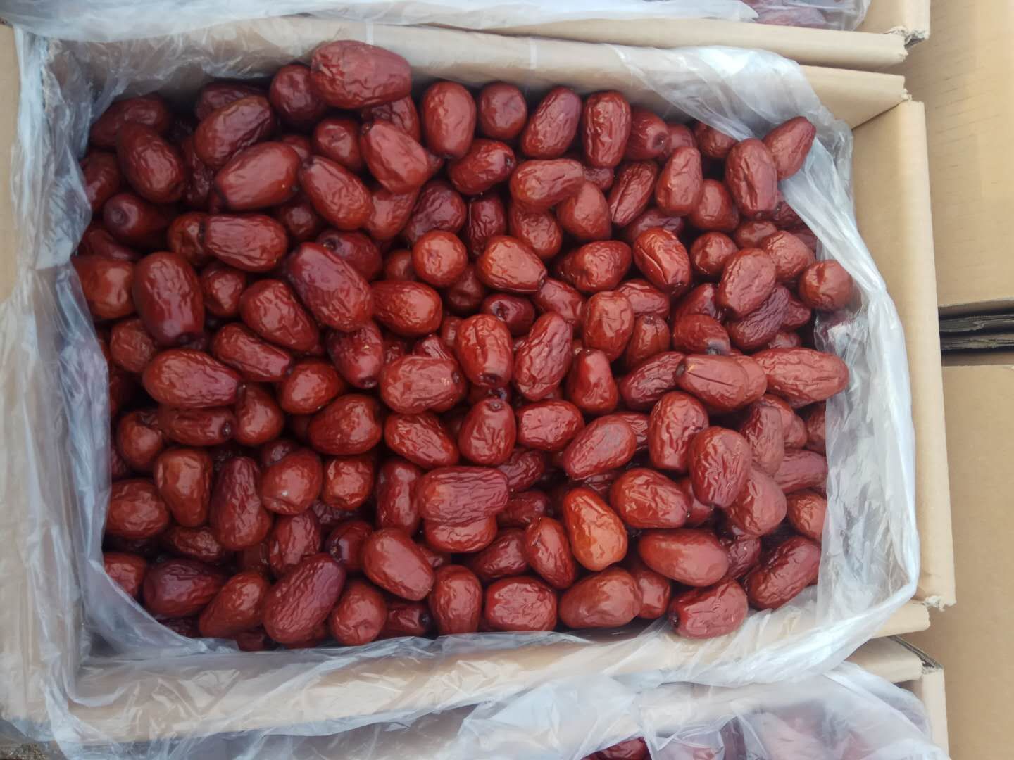 现代化仓储车间内,工作人员正在流水线上对新疆小骏枣进行称重、装袋、真空封装和贴标,背景有堆叠的纸箱和物流快递单,展示从产地直达消费者的高效供应链流程 新疆小骏枣电商打包现场