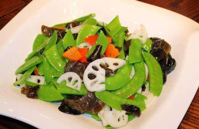 一盘色彩丰富的炒荷兰豆,搭配胡萝卜片和木耳,色香味俱佳 荷兰豆与胡萝卜、木耳一起炒制的美食