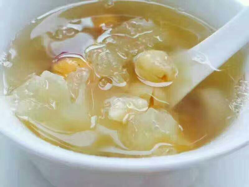一碗正在炖煮的银耳莲子羹,汤汁微稠,可见白色莲子与银耳交织,热气腾腾,旁边摆放干莲子原料作为对照,体现从原料到成品的过程 莲子烹饪应用场景