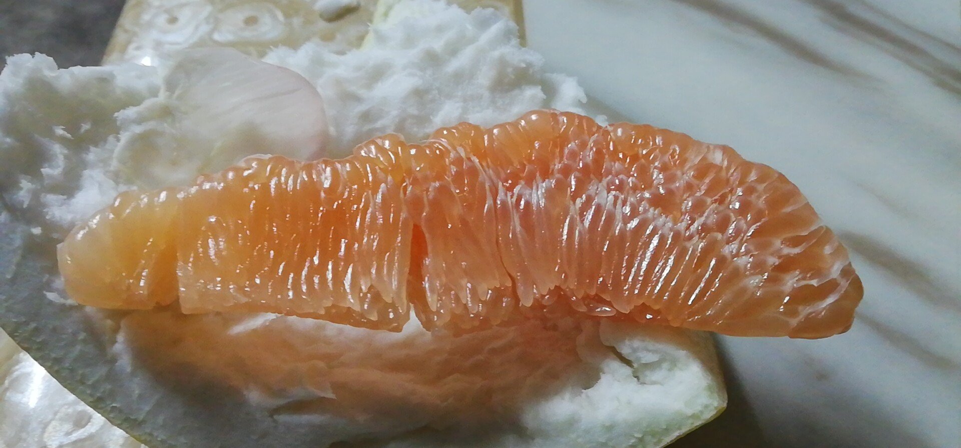 成熟的太东蜜柚被横向切开,露出粉红色的果肉,汁胞饱满晶莹,果瓣清晰分明,周围摆放着测量工具如游标卡尺和糖度仪,背景为实验室工作台,体现专业检测场景 果实切面特写