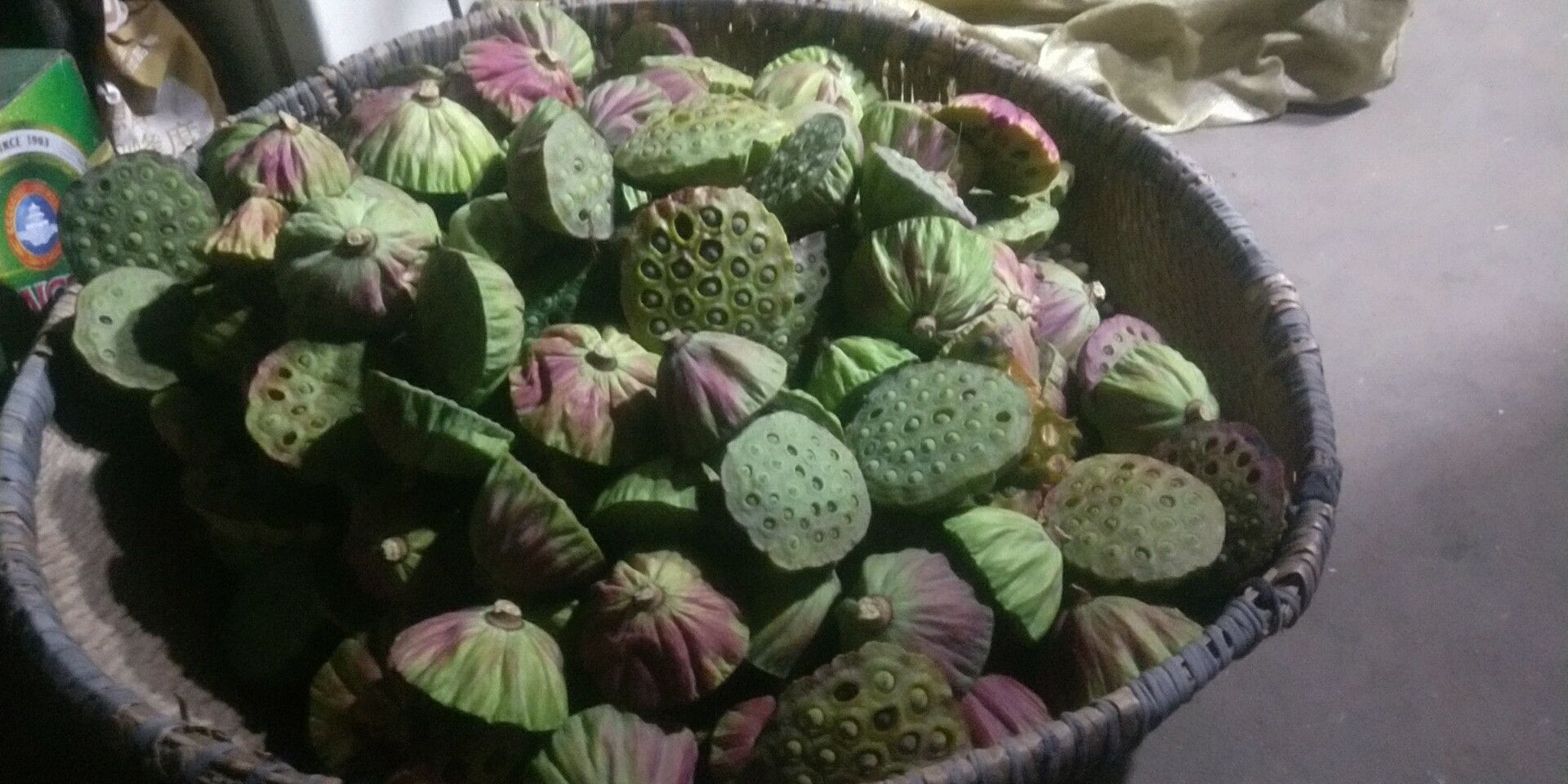 左侧为剥开的新鲜莲蓬,露出多颗青绿色带壳莲子;右侧为干燥处理后的棕色莲子,部分已去壳并展示内部结构,其中一枚被剖开显示绿色莲心,背景附有常见莲子制品标签 干制莲子与新鲜莲蓬对比图