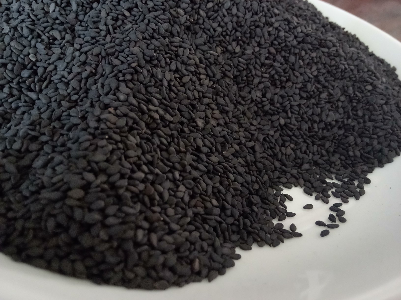 一盘新鲜的黑芝麻,颗粒饱满,色泽乌黑,展示其自然形态 黑芝麻特写